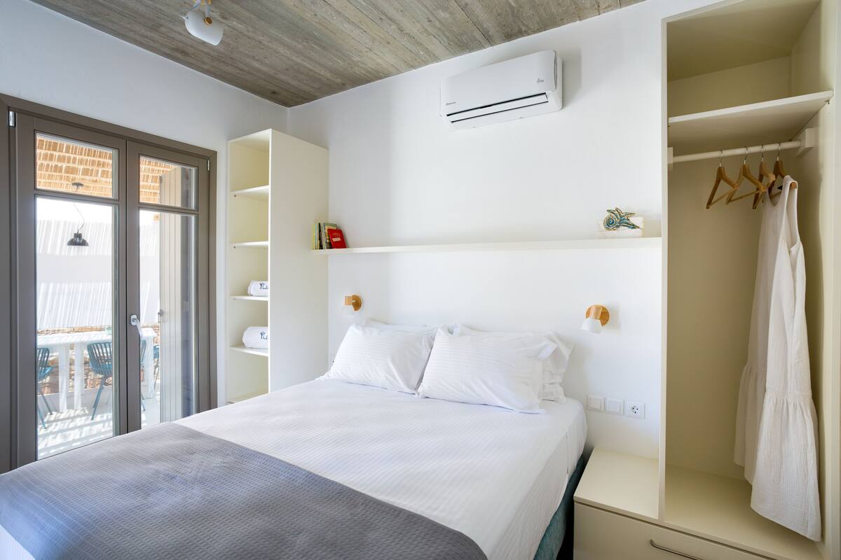 A bedroom with a bed, built-in wardrobe, and a window with a view of the outside.