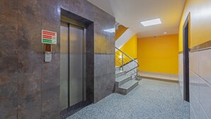 Un ascensor con instrucciones de emergencia y una escalera con barandilla de metal.