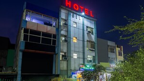 Un edificio de hotel con un llamativo letrero 'HOTEL', múltiples unidades de aire acondicionado y un letrero de 'treebo' que indica servicios cercanos.