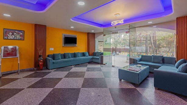 Un vestíbulo moderno con piso de diseño de cuadros, sofás azules y una pared de vidrio con letrero de salida.