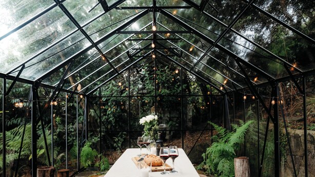 A greenhouse with a table set for a meal, surrounded by greenery and a glass ceiling. - Luxury Treetop Escape with a Garden glasshouse (Kalorama)