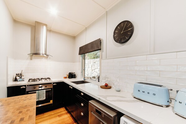 A modern kitchen with a stainless steel range hood, a double sink, and a wall-mounted clock. - Luxury Treetop Escape with a Garden glasshouse (Kalorama)