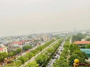 A cityscape with a wide road lined with trees and buildings. - Sao Mai Hotel by Bay Luxury (Hanoi)