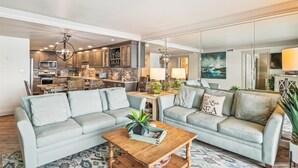 Un salon moderne avec un ensemble de canapés, une table basse et une cuisine en arrière-plan.