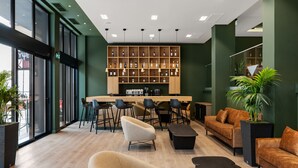 Een moderne loungeruimte met een bar, zitplaatsen en een groot aantal flessen.