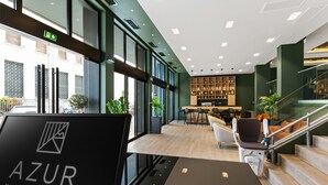 Een moderne hotel lobby met een receptiebalie, een zithoek en een trap.