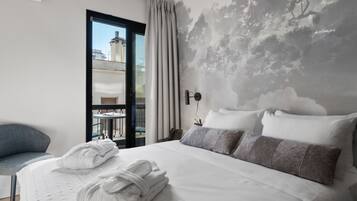 Hotelkamer met een bed, een stoel, uitzicht door een glazen deur en een muurschildering.