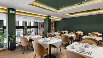 Enjoy dining in style with tables set for a sophisticated meal, surrounded by lush greenery and modern decor.