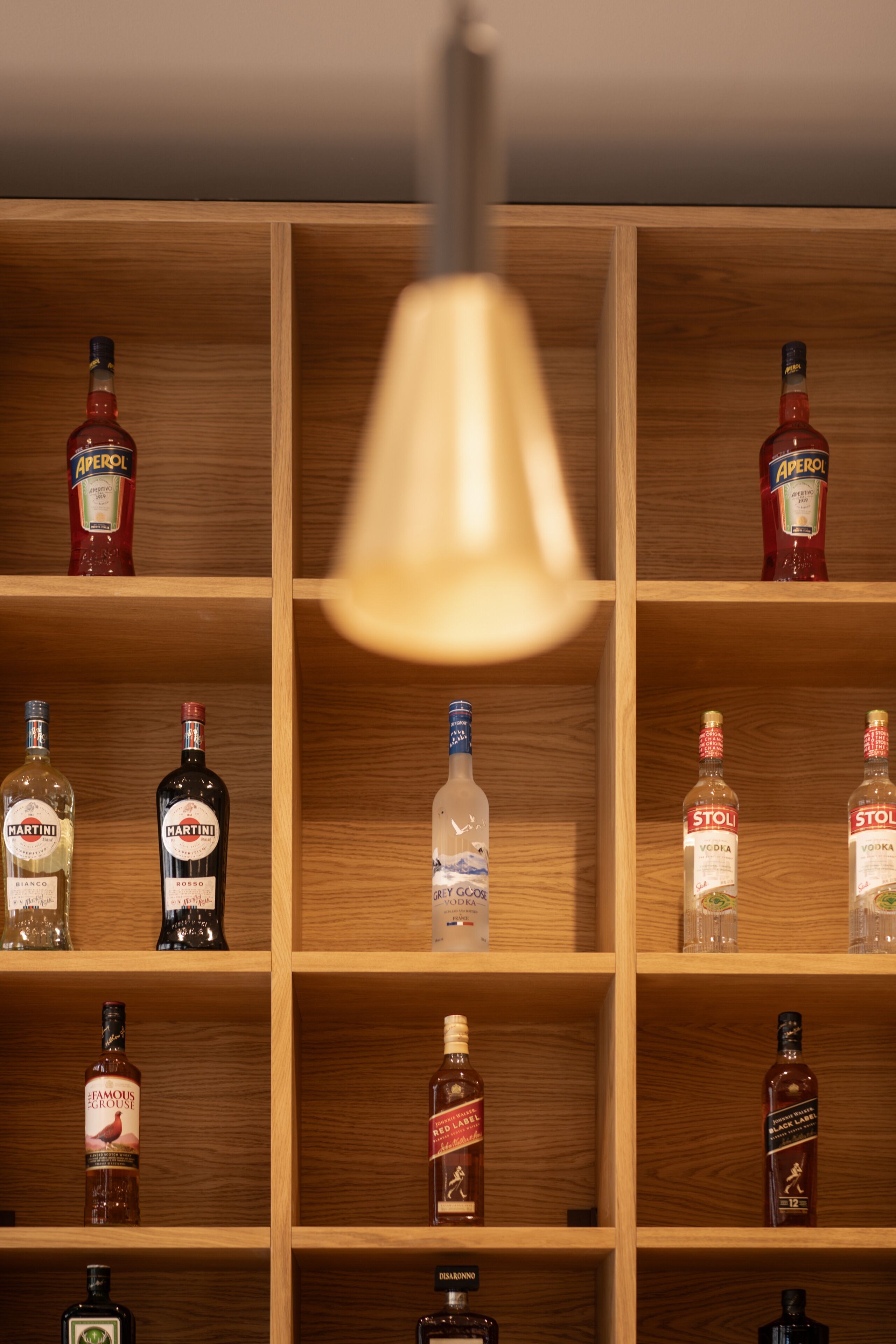 A wooden liquor cabinet with multiple shelves containing various bottles of liquor.