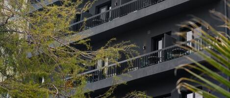 A multi-story building with balconies, surrounded by vegetation.