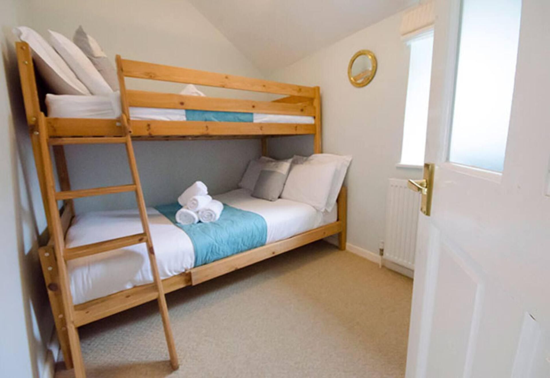 A bunk bed with a ladder, a window, and a radiator.