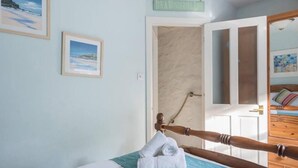 A bedroom with a bed, a wooden headboard, a towel, a framed picture, and a sign above the door. - Trelonie - a Fisherman's Cottage in St Ives Town (St Ives)