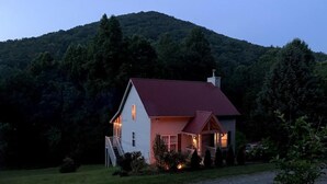 Una casa a due piani con tetto rosso, circondata da un vialetto in ghiaia e da un prato.