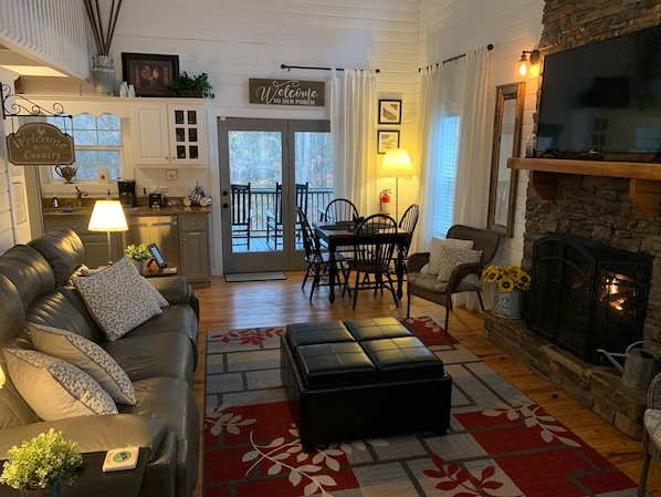 Una sala de estar acogedora con un sofá de cuero, una chimenea y un comedor con mesa y sillas.
