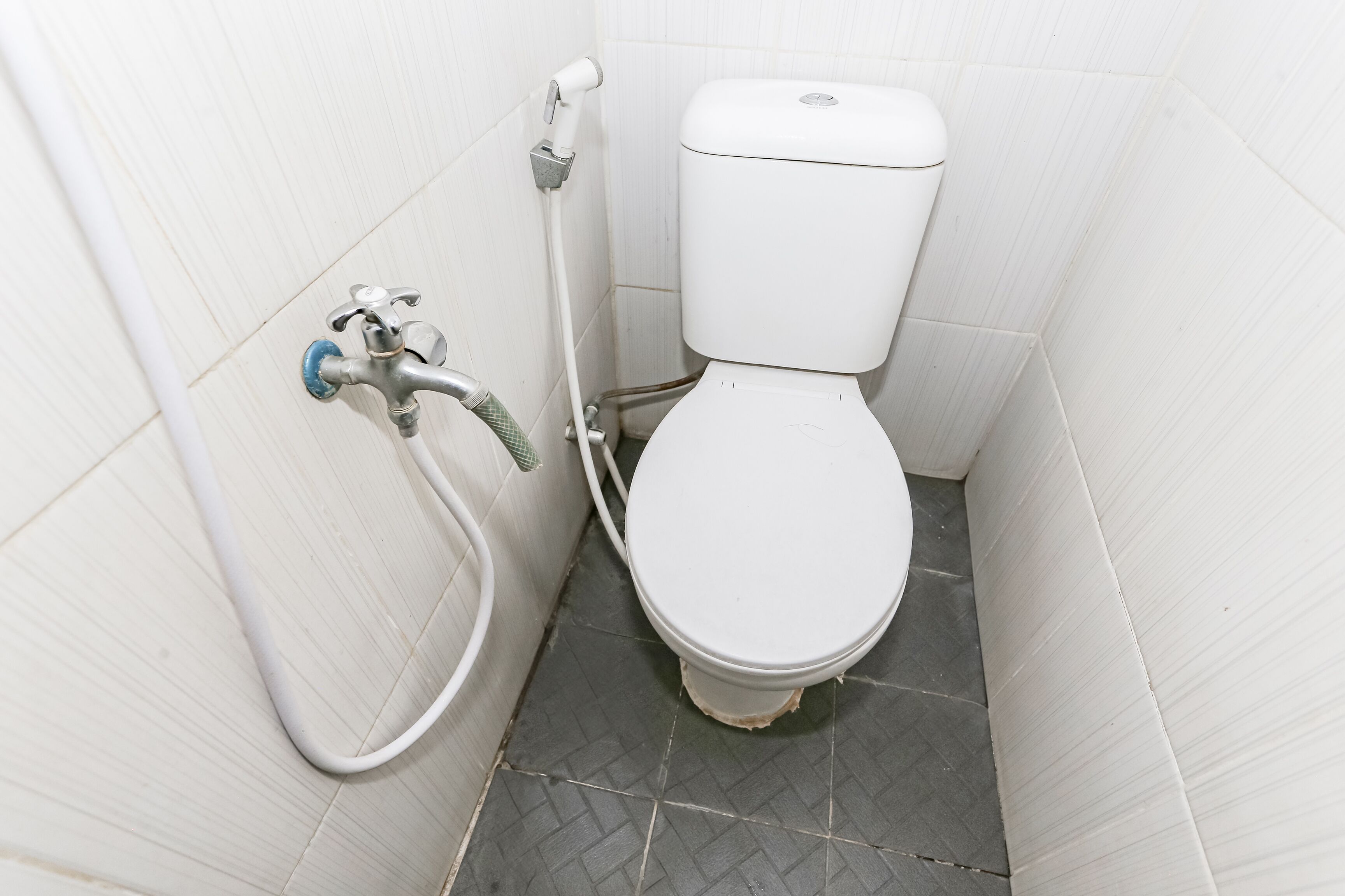 Un baño pequeño y blanco con inodoro, ducha y lavamanos fijado a la pared.