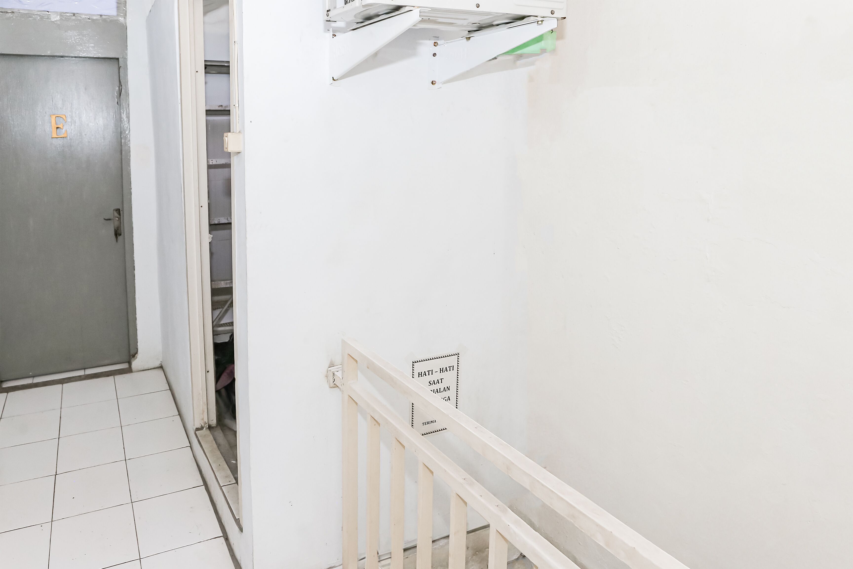 A hallway with a door labeled 'E', a staircase with a handrail, and a sign with text.