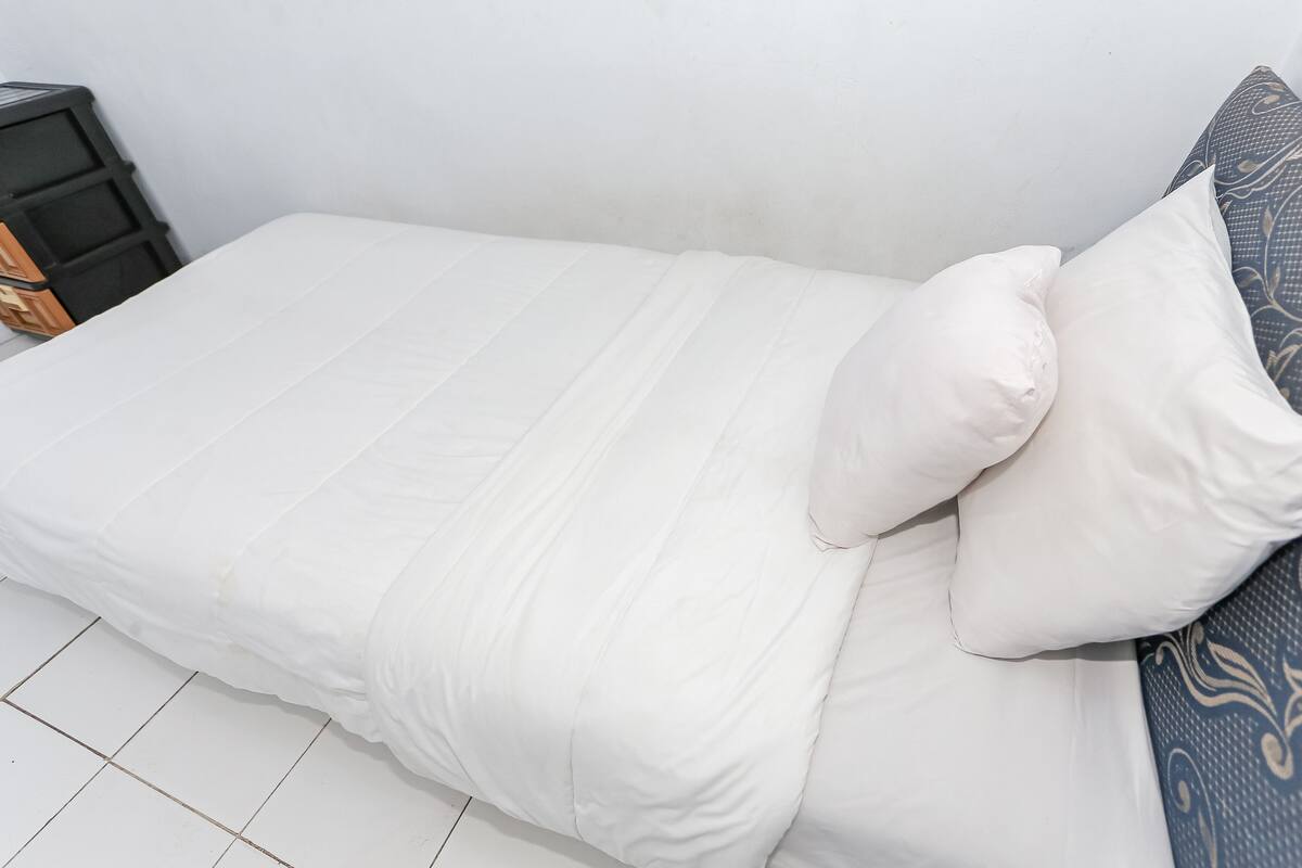 Un lit avec une literie blanche et un oreiller à motifs.