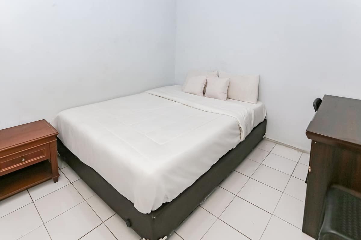 Une petite chambre à coucher, bien rangée, avec un lit, une table de chevet en bois et un bureau.