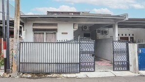 Uma entrada protegida por grades para um edifício, com portão de metal e área de estacionamento coberta.