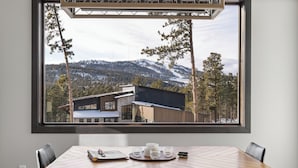 A dining area with a table and chairs, a window with a view of a mountain and forest, and a tray with glasses and a notebook. - Incredible View, Open Floor Plan, Paved Roads, Hot Tub, Access to Clubhouse! (Lead)