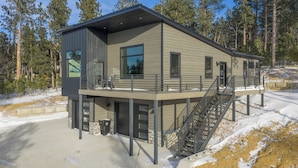 A modern two-story house with a covered outdoor area, a staircase, and a garage. - Incredible View, Open Floor Plan, Paved Roads, Hot Tub, Access to Clubhouse! (Lead)