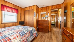 A wooden-paneled bedroom with a bed, dresser, and a television. - The Beach Box - Kitty Hawk MP 4.5, Ocean View, 240 Yds to Beach, Pets OK, Flex Stays (Kitty Hawk)