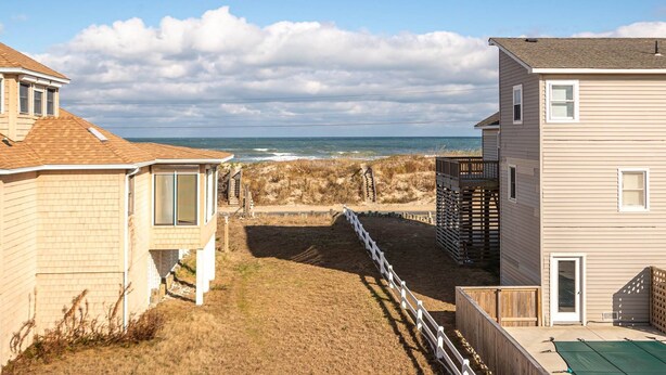 A coastal property with a view of the ocean, featuring a wooden deck and a fenced area leading to the beach. - The Beach Box - Kitty Hawk MP 4.5, Ocean View, 240 Yds to Beach, Pets OK, Flex Stays (Kitty Hawk)