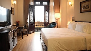 Una habitación de hotel con una cama, un escritorio con silla, un televisor y una ventana con cortinas.