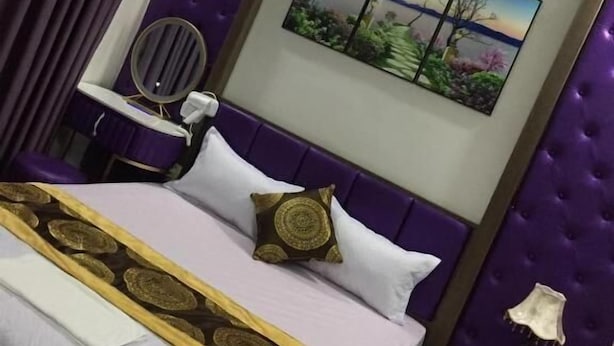 A neatly arranged bedroom with a bed, a chair, a nightstand, and a wall-mounted painting. - Anh Sao Hotel by Bay Luxury (Hanoi)