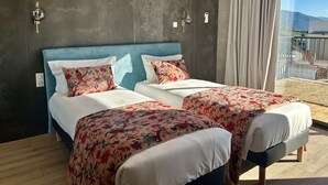 A hotel room with a large bed, two bedside tables, a window with a view, an air conditioning unit, and a curtain. - Hôtel Casa Matteu (Afa)