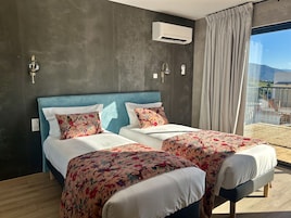 Habitación de hotel con una cama grande, dos mesitas de noche, una ventana con vistas, un equipo de aire acondicionado y una cortina.