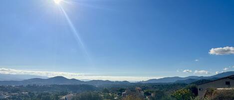A rural landscape with a clear sky, distant mountains, and scattered buildings.
