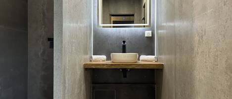Un baño moderno con un espejo rectangular, un lavabo blanco y un perchero para toallas.