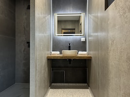 Un baño moderno con un espejo rectangular, un lavabo blanco y un perchero para toallas.