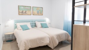 Ein Schlafzimmer mit zwei Betten, einem runden Beistelltisch und einem Kunstwerk an der Wand.