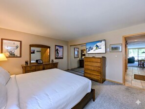 Une chambre d’hôtel avec un lit, une commode, une télévision et un miroir.