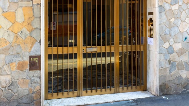 Une façade en pierre, une porte en métal et une petite enseigne fixée au mur.