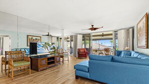 Ein geräumiges Wohnzimmer mit einem blauen Sofa, Holzmöbeln und einem Fernseher.