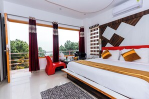 A modern hotel room with a large bed, a balcony with red curtains, a red chair, and a view of greenery. - Saalak Lite Eliot Exotica  (Dharamshala)
