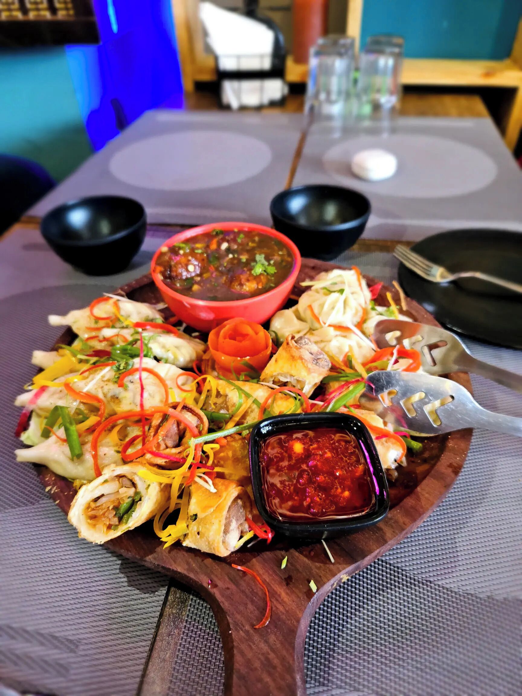 Una mesa con diversos platos, entre ellos un tazón de sopa, una fuente de dumplings y un recipiente pequeño para salsa.