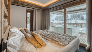 Un dormitorio con una cama grande, vistas a un paisaje nevado y un balcón.
