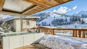 A wooden deck with a hot tub overlooking a snowy mountain landscape. - Les Chalets de La Clusaz - Appartement Le Faon (La Clusaz)