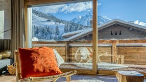 A cozy room with a large window overlooking a snowy mountain landscape. - Les Chalets de La Clusaz - Appartement Le Faon (La Clusaz)