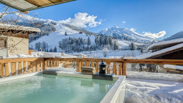 A hot tub with a wooden deck and a view of snow-covered mountains. - Les Chalets de La Clusaz - Appartement Le Faon (La Clusaz)