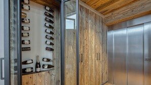 A wine rack with bottles, a wooden cabinet, and a metallic elevator door.