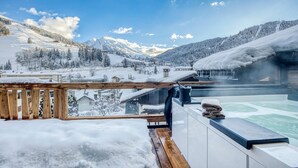 A snow-covered mountain landscape with a wooden deck and a hot tub.