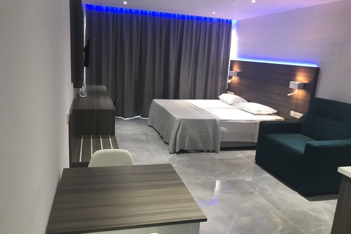A hotel room with a bed, a sofa, a table, and a TV.