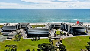 Ein Hotel mit mehreren Gebäuden, einem Parkplatz und Blick auf den Strand.