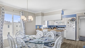 Een moderne keuken met witte kasten, een glazen eettafel en uitzicht op het exterieur.