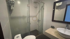 Un baño con ducha envuelta en vidrio, inodoro, lavabo y espejo.